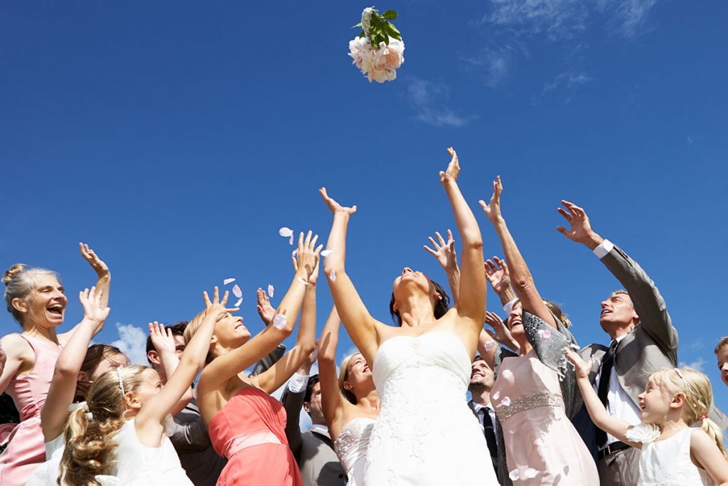 a bride throwing her wedding bouquet, and the guests are trying to catch it